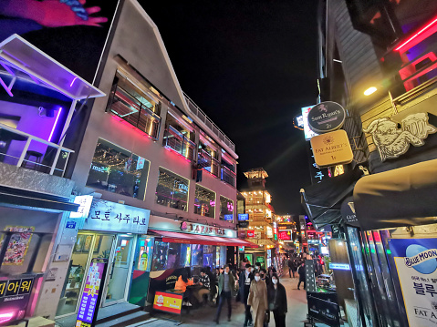 Seoul, South Korea - October 25, 2022: Itaewon famous night entertainment alley with many people on the stree at night. There are many people wear face masks.