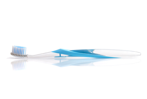 Toothbrush on reflective surface, with white background