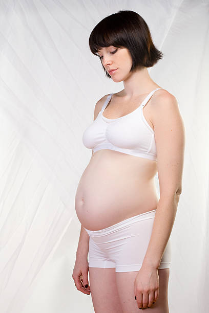 vue latérale d'une femme enceinte dans son sous-vêtements - table chair white curve photos et images de collection