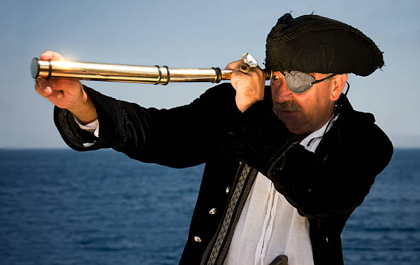 pirate captain looking through a spyglass A pirate captain of the Mediterranean, looking through a hand-held spyglass / telescope. historical reenactment stock pictures, royalty-free photos & images