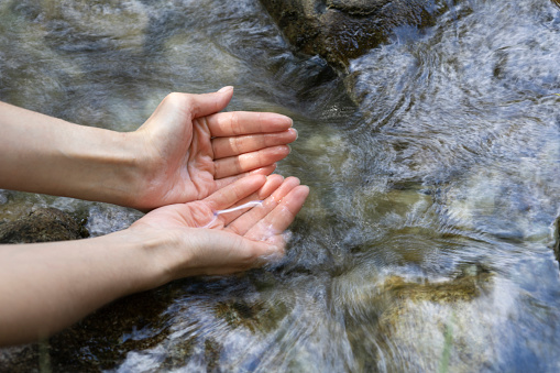young woman putting her hands in a river