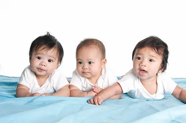 Three cute babies who are five months old.  The first two are twins and the third is their first cousin born within a week of them.  They could represent triplets.Here are the same babies at nine months old