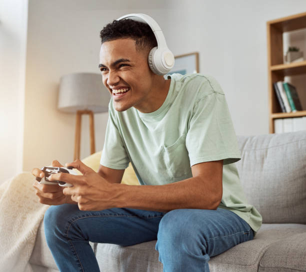 istock Home, game controller and man with headphones, smile and relax on a couch, stress relief and internet. Happy person, gamer and guy on a sofa, playing online and headset with audio, sound and esports 1729549204