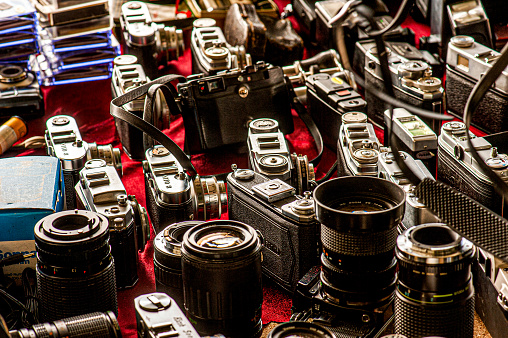 A couple of vintage cameras on a flea market. The image shows as close-up several old used photo cameras.