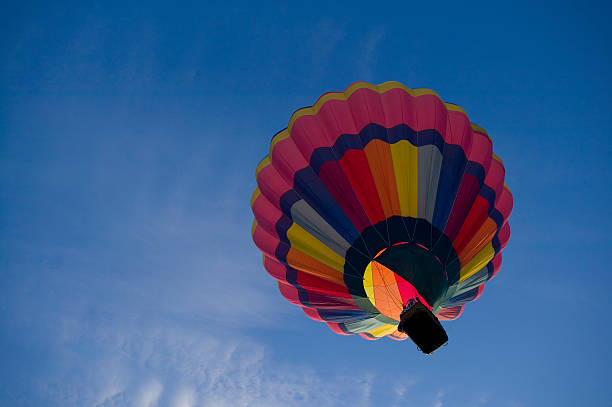 Hot air balloon rising into a blue sky stock photo