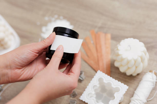 istock Woman hand holding handmade candle jar with white label with space for text 1729566149