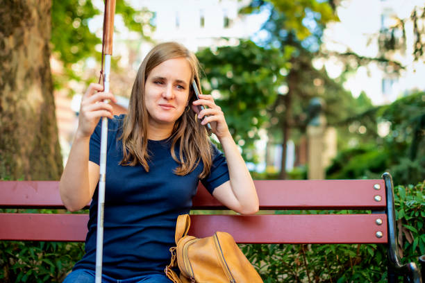 istock A visually impaired woman with white cane sitting on the park and having a call 1729567470