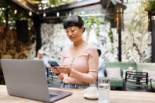 Modern woman looking at her smartphone while sitting at the caffe