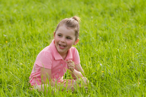 young girl sitting in a meadow smiling