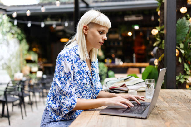 Close-up of a woman drinking coffee and working on a laptop