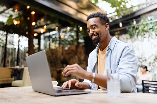 Modern black man working on a laptop at the cafe