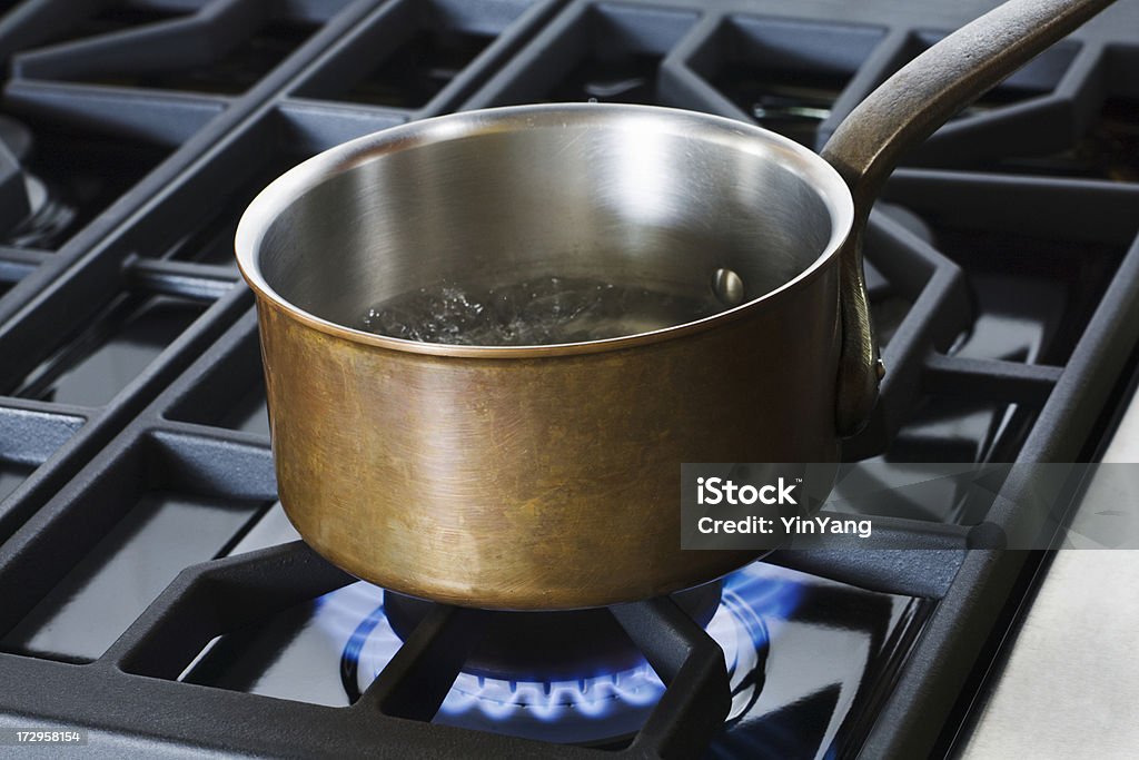 Copper Pan on Gas Stove Hz Subject: A copper pan resting on the burner of a stove. Cooking Pan Stock Photo