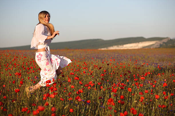 A beautiful plus size girl with white hair in a summer dress poses on the street with daisies. Chubby girl in a meadow with daisies close-up.