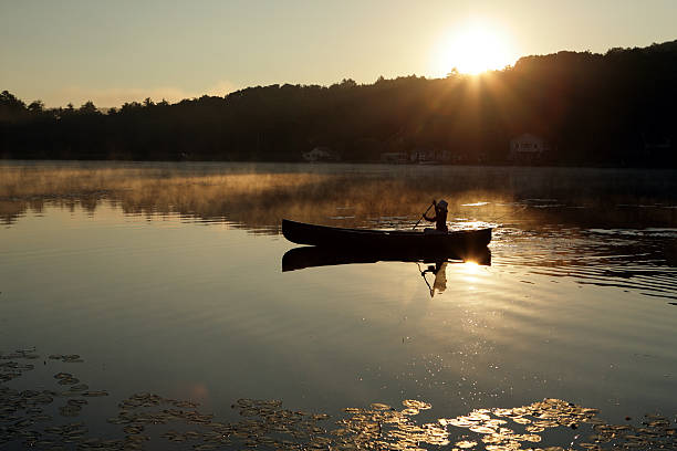 istock Outdoors girl paddling canoe on lake backlit sunrise 172958908