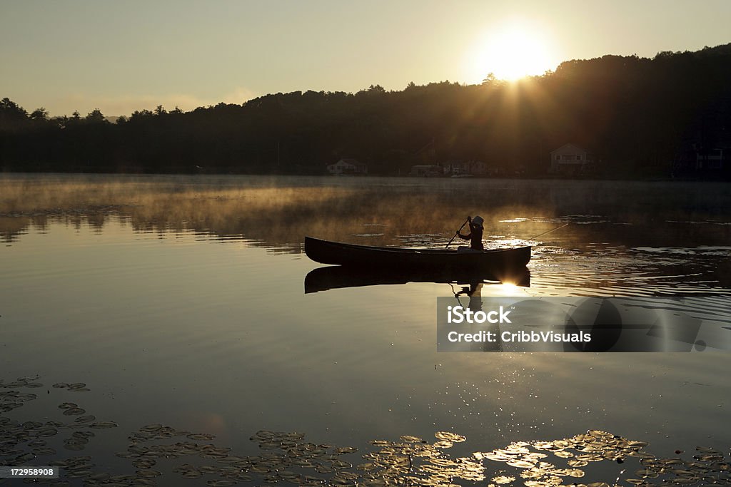 Ao ar livre de rapariga Remar Canoa no Lago retroiluminado nascer do sol - Royalty-free Canoa Foto de stock