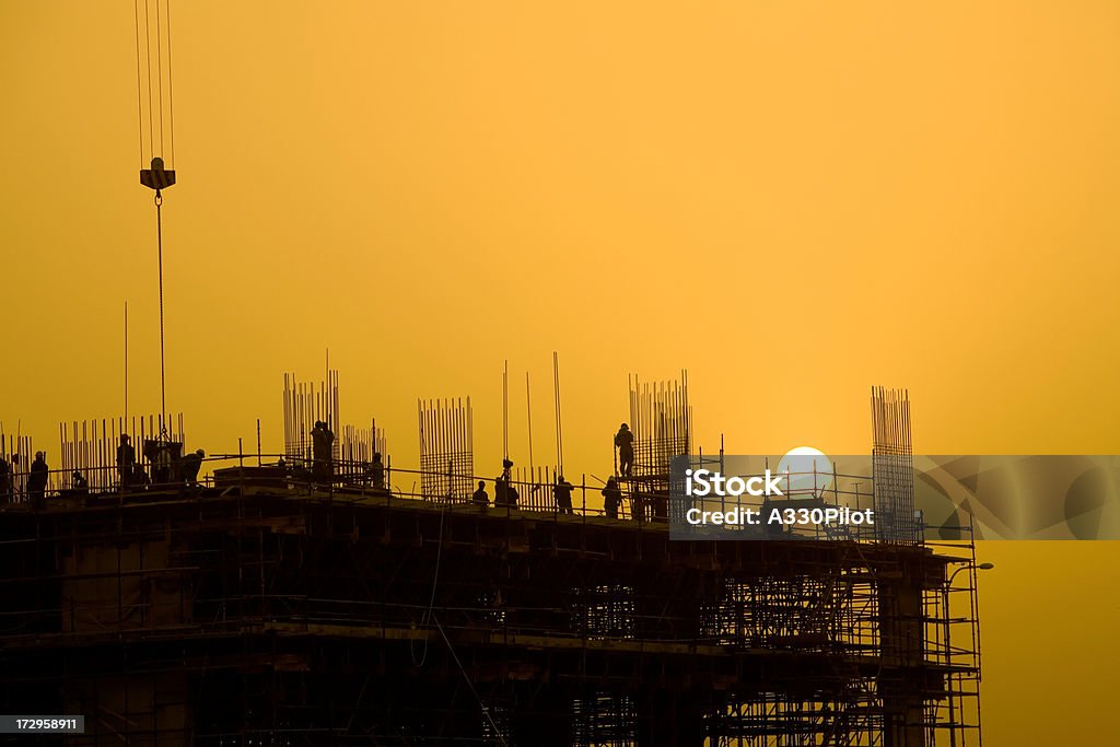 Sunset Construction Building construction at sunset with workers in view. Construction Site Stock Photo