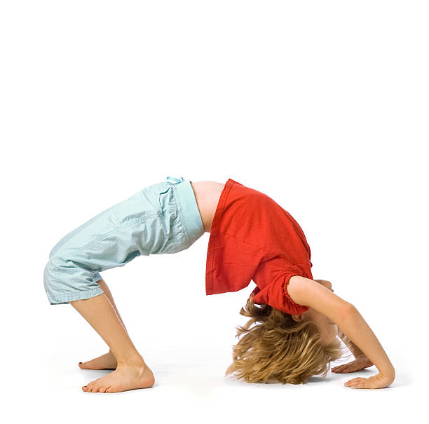 Child doing a yoga wheel pose on the ground stock photo