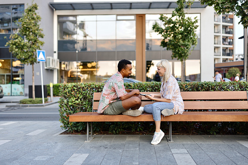 Lovely multiracial people sitting on a bench and talking