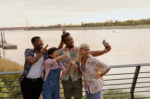 Joyful multiracial friends taking a selfie next to the river