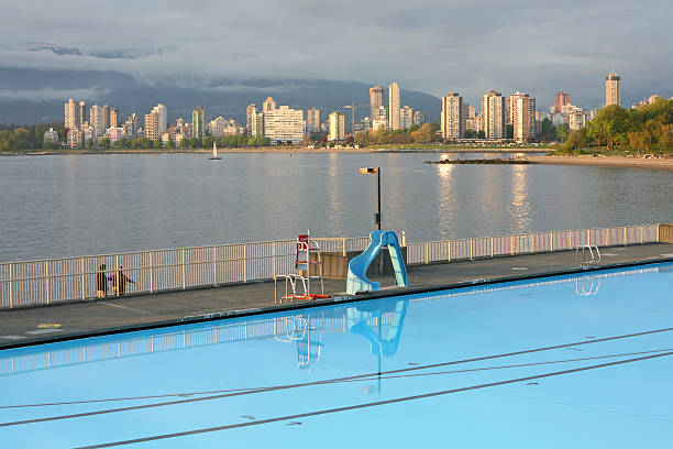 Evening Light After The Rains. Vancouver English Bay From Kitsilano Telephoto of Early evening after a spring rain. Huge Olympic size swimming pool in foreground. beach english bay vancouver skyline stock pictures, royalty-free photos & images