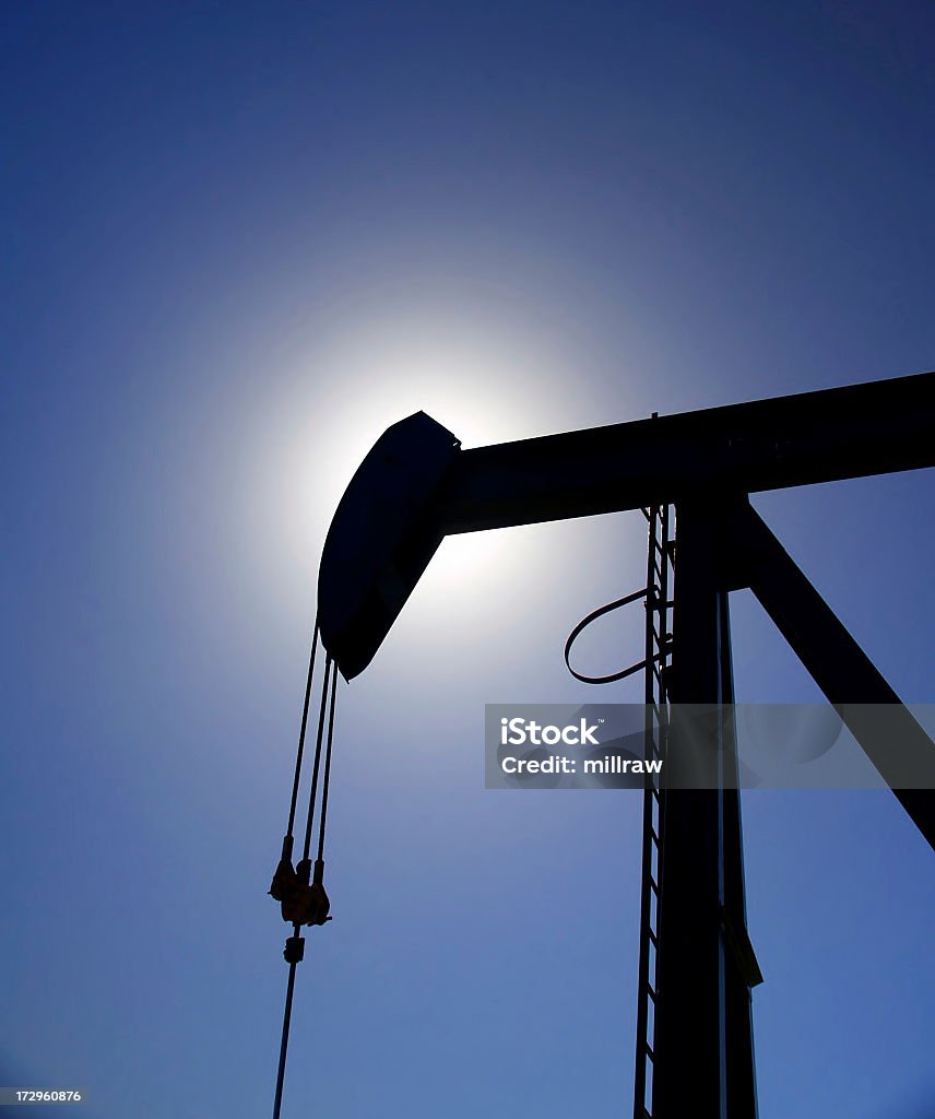 Aceite Pumpjack Silhouetted contra el cielo azul - Foto de stock de Alberta libre de derechos