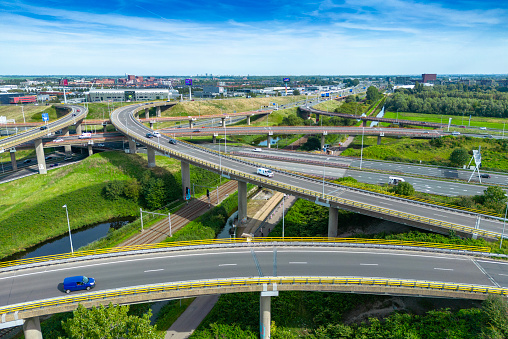 Aerial view of traffic and overpasses, city skyline on the horizon. Descending vertical drone shot.