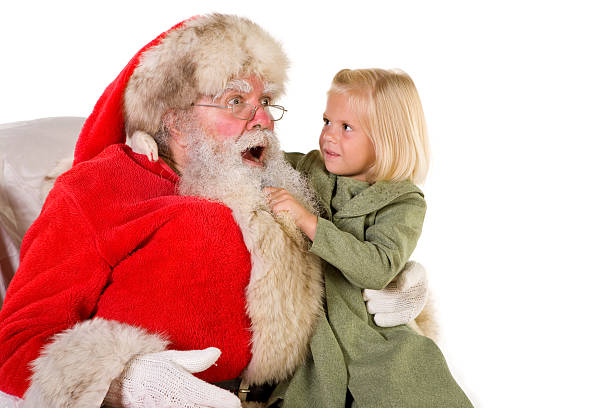 Demanding little girl pulls Santa's beard stock photo
