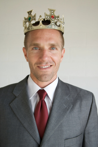 Businessman wears a crown as he smiles for the camera