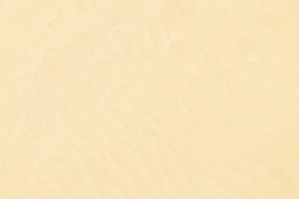 Close-up on golden sand texture on a sunny summer day. Selective focus, low angle view.