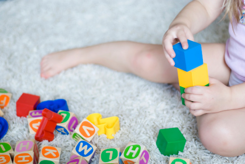 Kid playing with play blocks on carpet.
