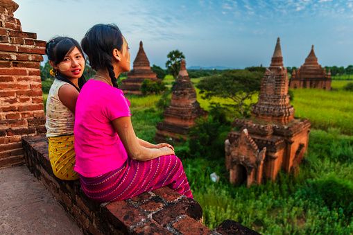 Young Burmese girls with thanaka face paint looking at an ancient temples of Bagan, Myanmar (Burma)