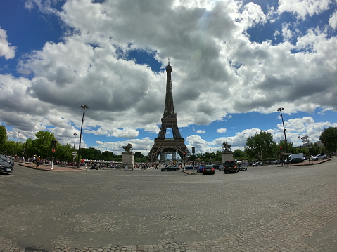 The Eiffel Tower seen in Springseason with a large Squar ebefore it with some traffic.