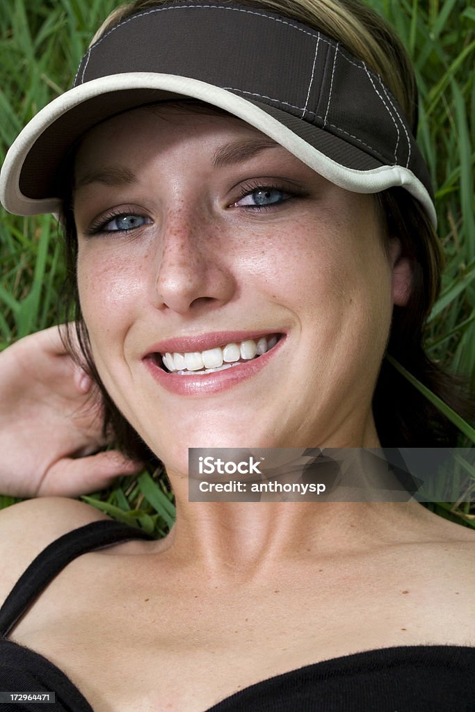 visor Young female lying in the grass wearing a visor. Cap - Hat Stock Photo