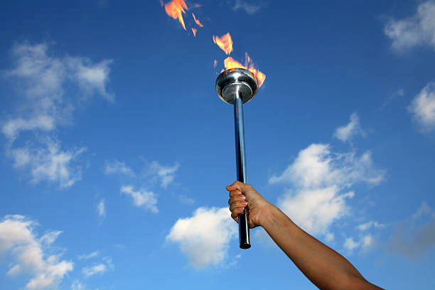 glory of holding flaming torch silhouetted hand holding burning flaming torch over cloudy sky.  flame photos stock pictures, royalty-free photos & images