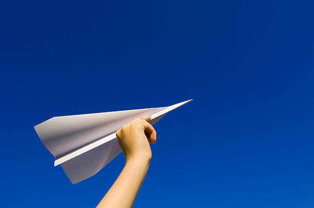 istock Child's hand lifting paper airplane on blue background 172965281