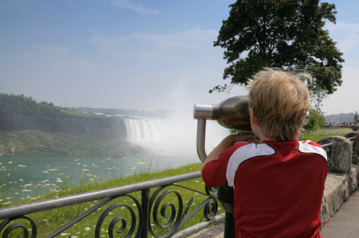 Young boy loooking throuch binoculars at Niagara Falls