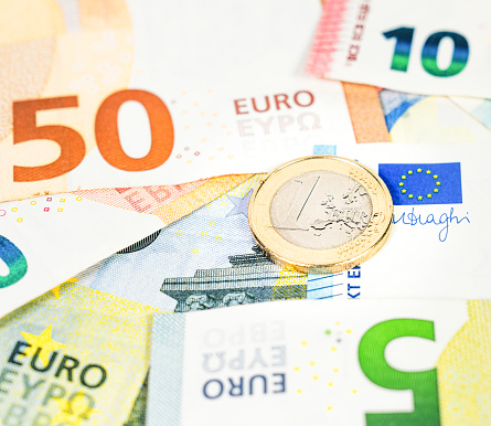 Macro photograph of a 1 Euro coin on top of a collection of Euro banknotes.