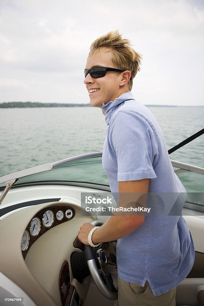 young man boating young man driving a boat with a relaxing smile. Activity Stock Photo