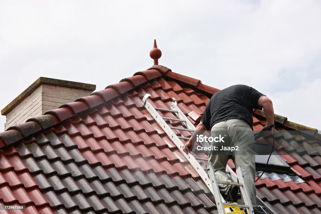 Um Homem no telhado, limpando os azulejos com Lavador por pressão - Foto de stock de Telhado royalty-free