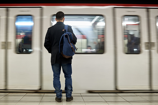 Young man standing in front of subway train