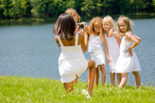 Four little girls pose by a lake for their friend
