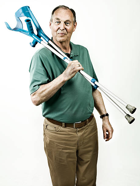 old man with crutches smiling old man carrying crutches over his shoulder comb over stock pictures, royalty-free photos & images