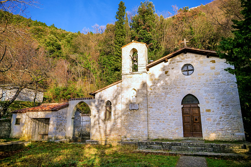 The small church of the ancient hermitage of Santo Marzio (Saint Martius), among the wooded mountains of Gualdo Tadino, a medieval village between Spoleto and Gubbio in the Italian region of Umbria. This hermitage was built around 1219 by the first Franciscan monks who arrived in these mountains, becoming a place of penance and prayer. According to official sources, this hermitage was visited by St. Francis of Assisi in 1224. The Umbria region, considered the green lung of Italy for its wooded mountains, is characterized by a perfect integration between nature and the presence of man, in a context of environmental sustainability and healthy life. In addition to its immense artistic and historical heritage, Umbria is famous for its food and wine production and for the quality of the olive oil produced in these lands. Image in high definition format.