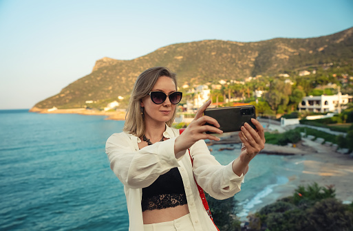 Woman takes selfie on the seashore during vacation.