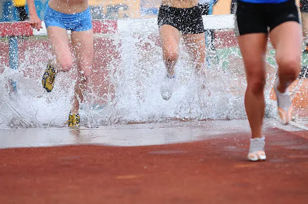 Runners at water jump during steeplechase event, low section