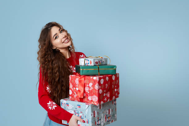 istock Happy woman holding stack of gift boxes over blue studio background. Winter Holidays Celebration, New Year  And Xmas Gifts Concept 1729727269