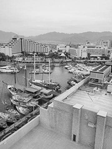 Eilat waterfront marina with boats infront of King Solomon hotel and Lagoona hotel both by Isrotel in black and white