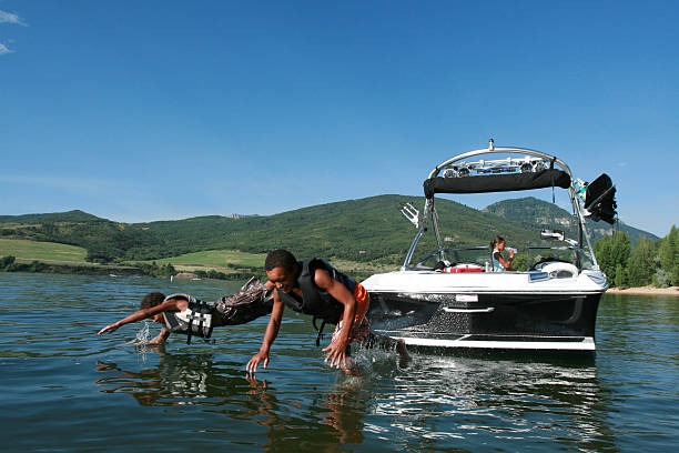 deux garçon sauter depuis le bateau - life jacket little boys lake jumping photos et images de collection