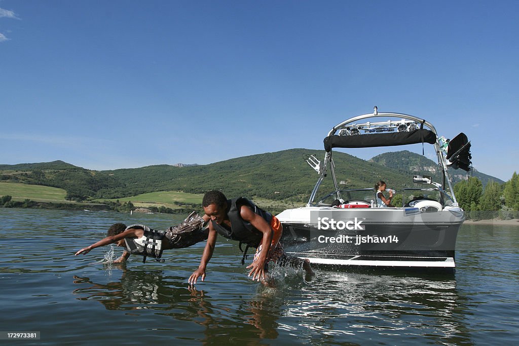 Два мальчика, прыгая от лодке - Стоковые фото Озеро роялти-фри