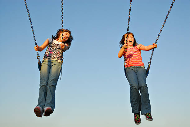 A twin sisters swinging happily on a sunny day